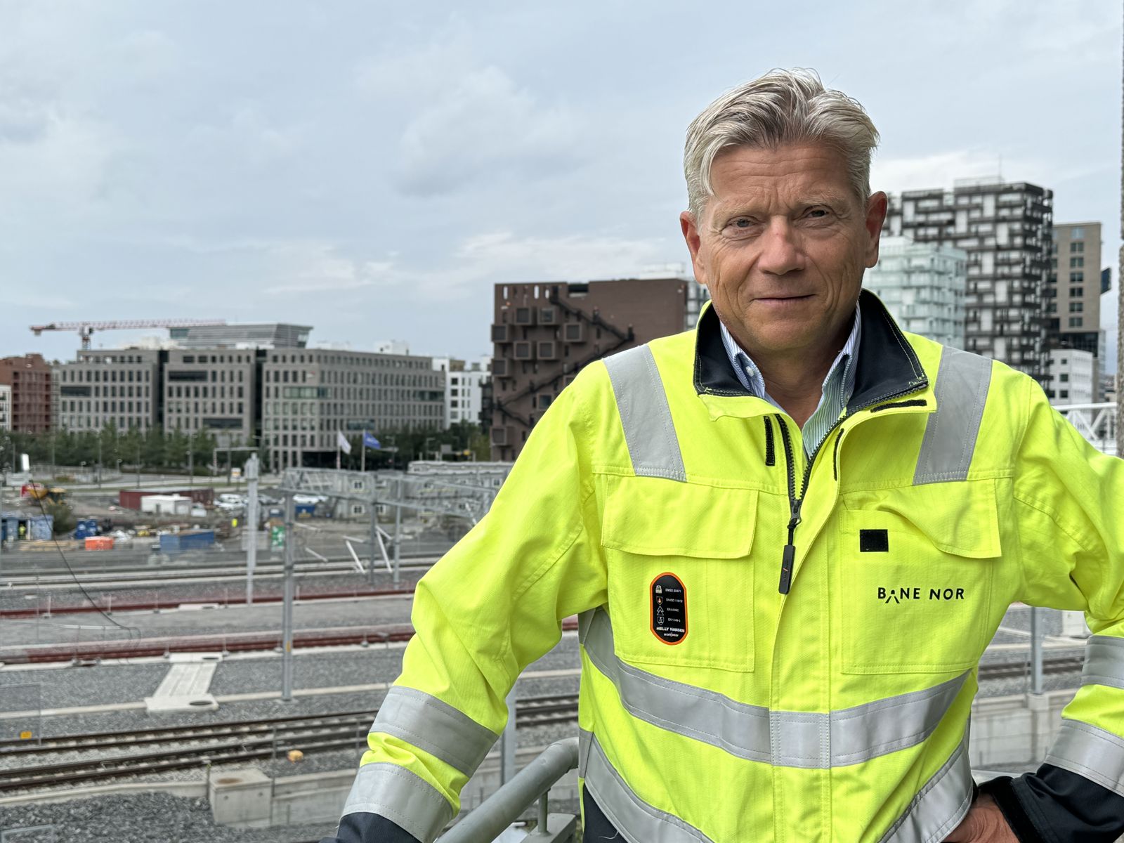 Mann i gule arbeidsklær med jernbaneskinner i bakgrunnen.