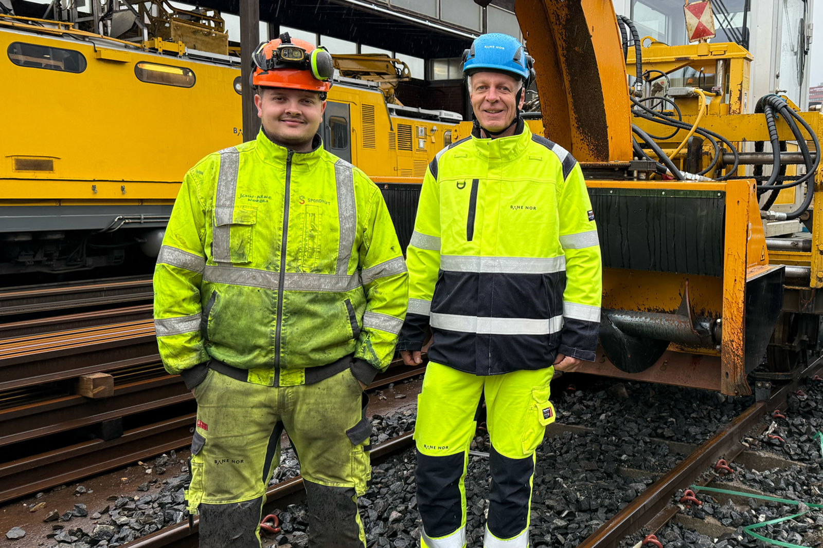 Menn i gule arbeidsklede foran snøbrøytemaskin.