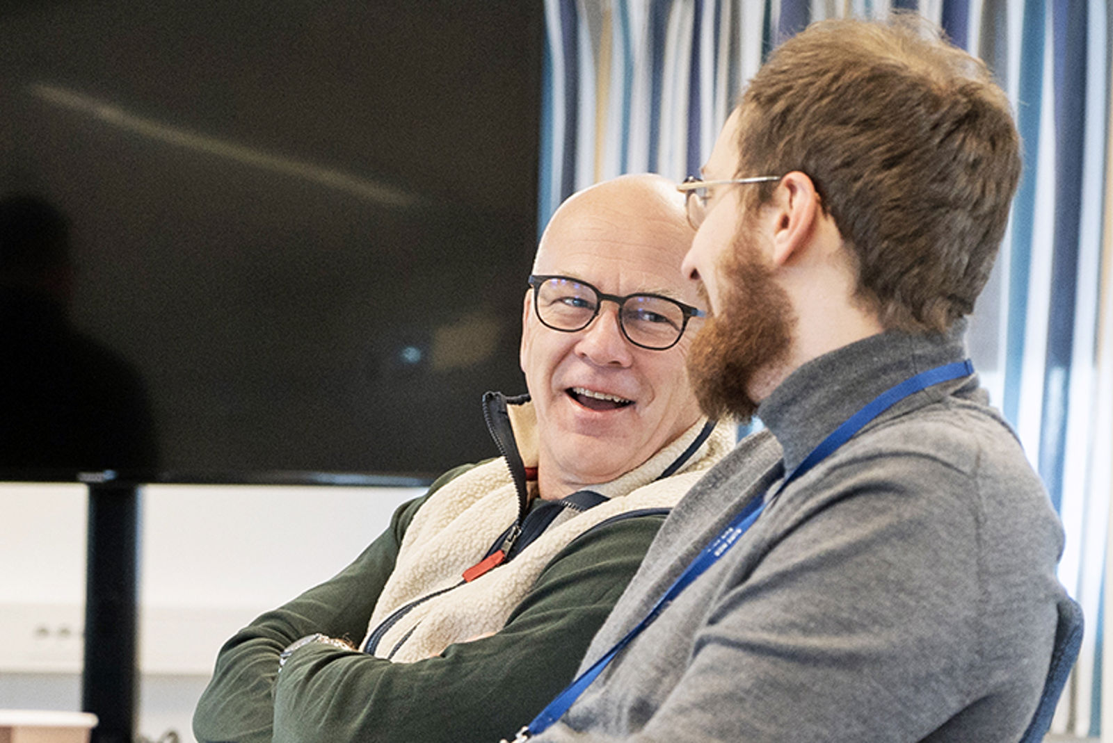 To menn snakker smilende sammen.