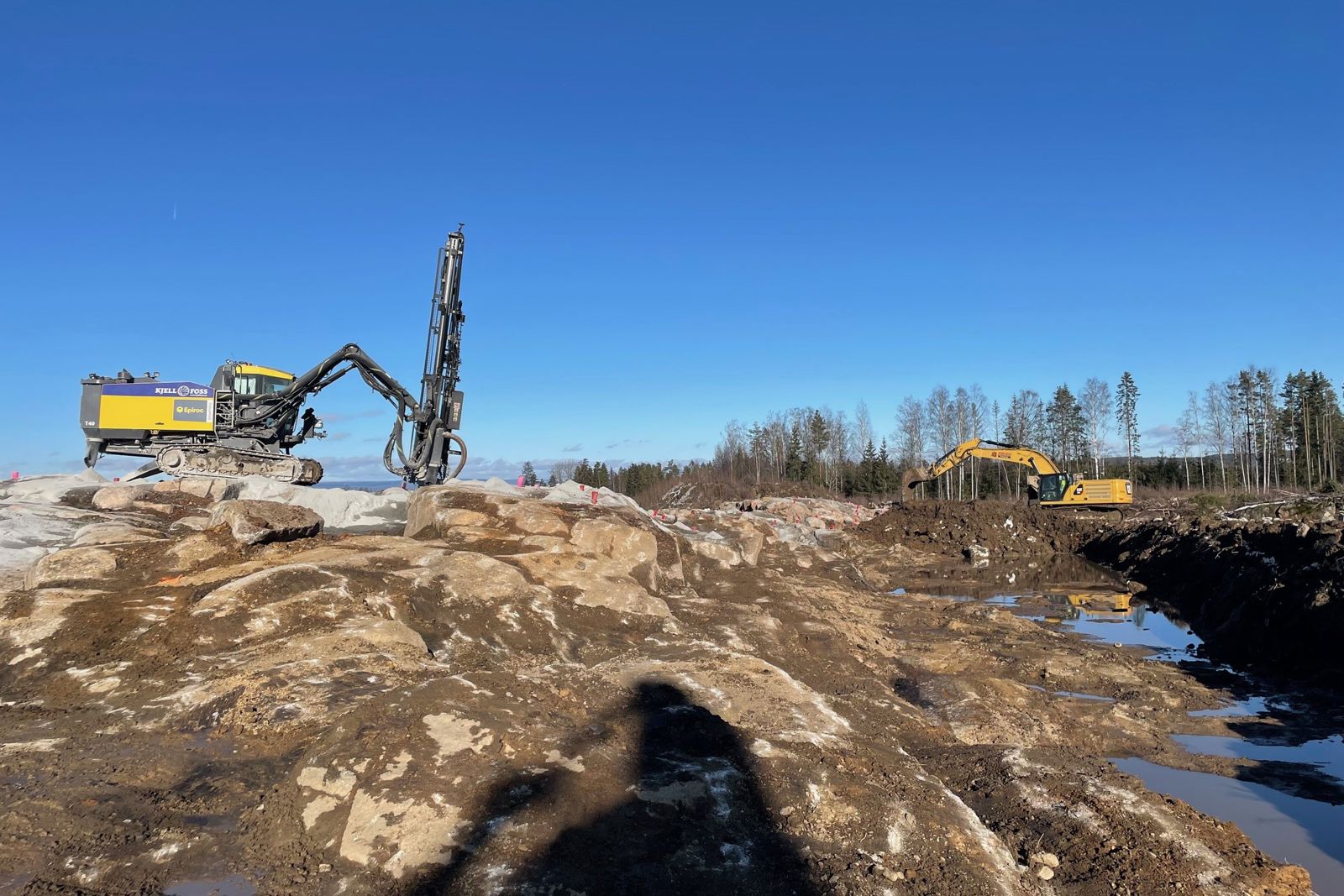 Anleggsmaskiner borer og rensker grunn. 