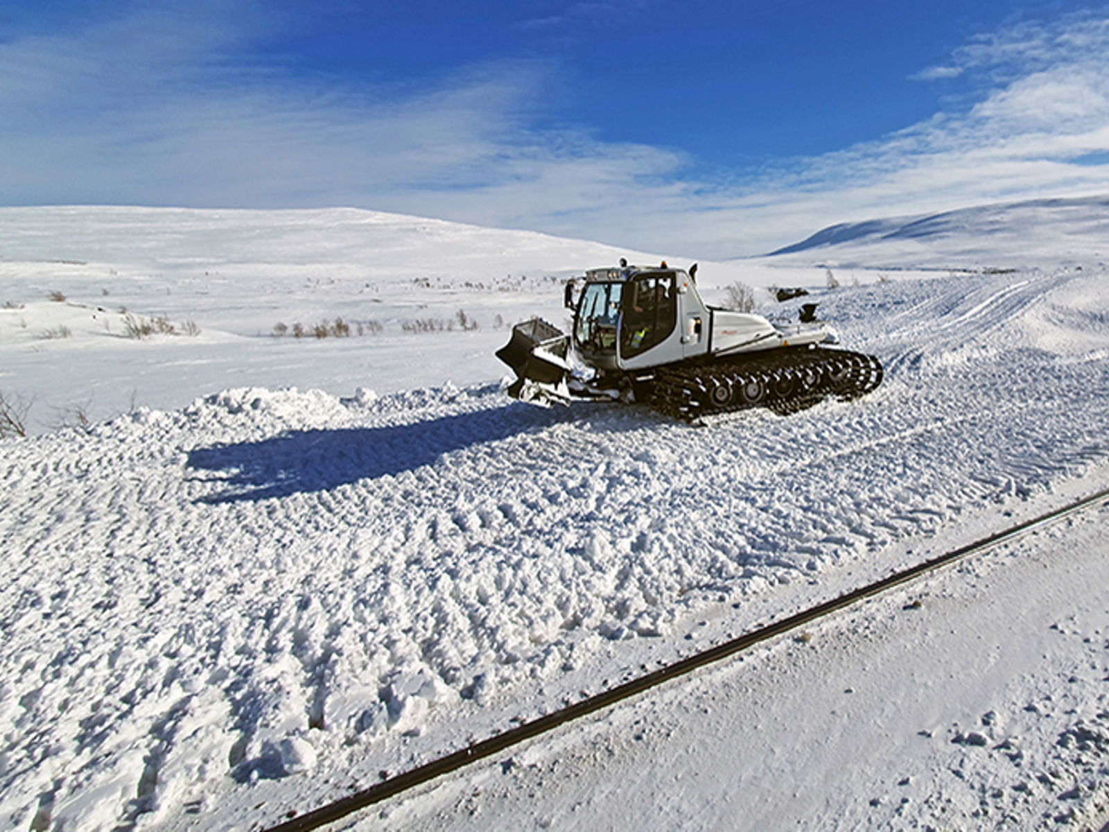 Bilde av en tråkkemaskin ved et jernbanespor på Saltfjellet.