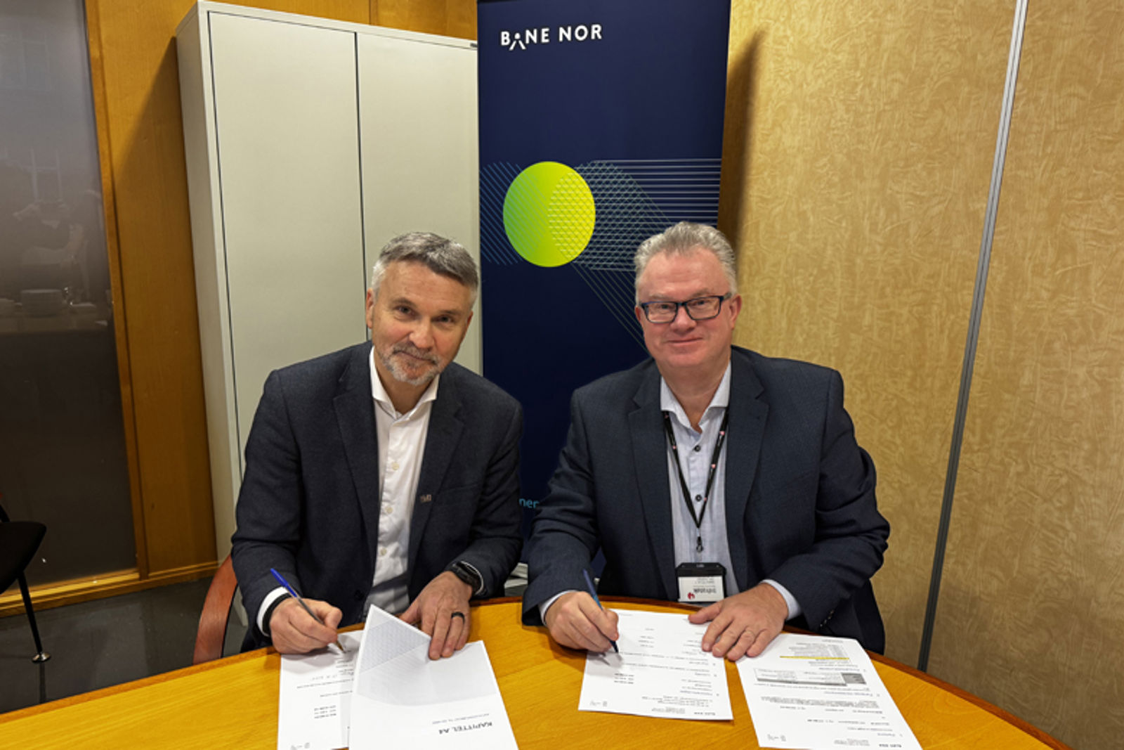 De to direktørene mens de signerer kontrakten 