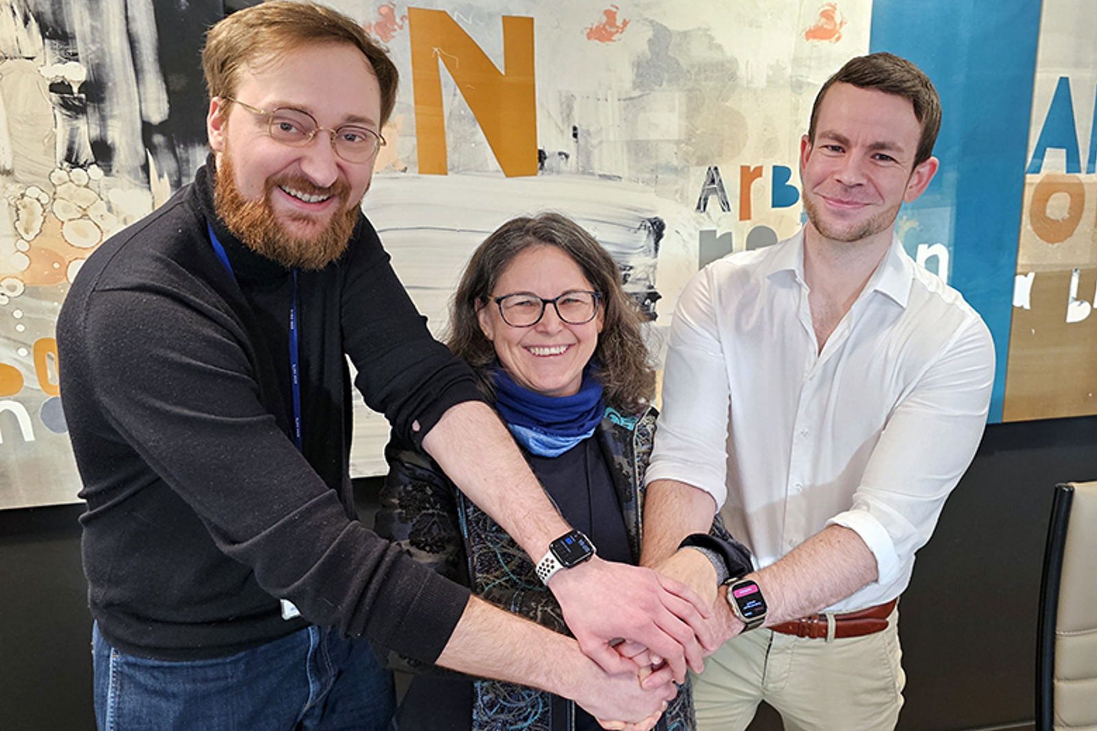 Tre glade personer holder hverandre i hendene