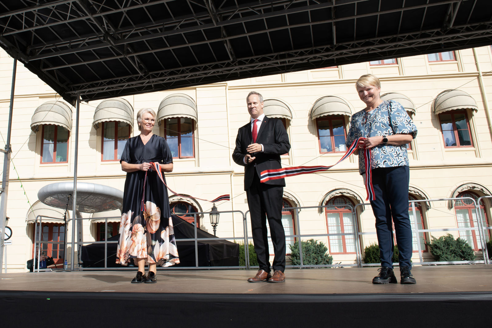 Mann klipper snor med flagg som to kvinner holder 