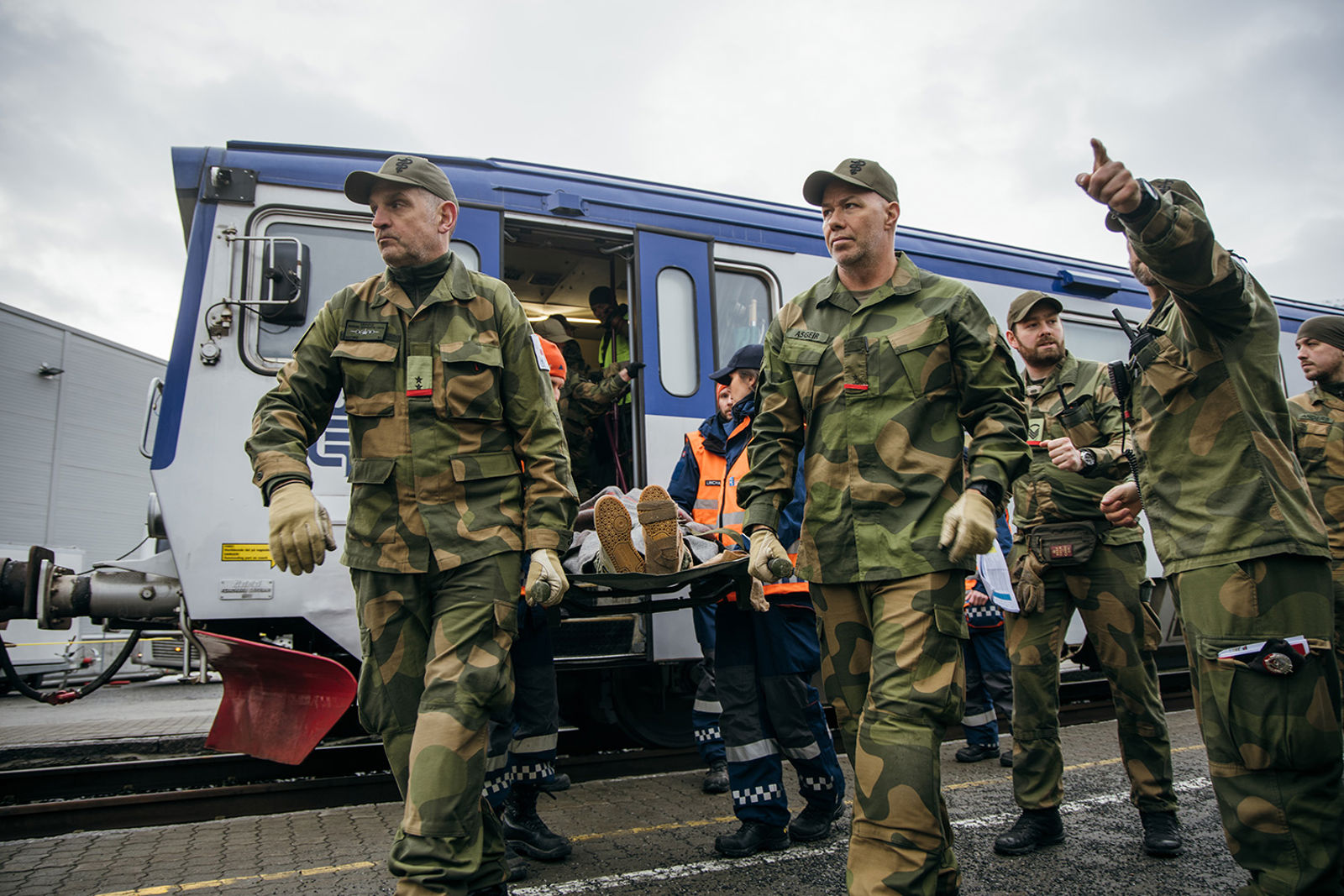 Uniformert sanitet bærer en båre med en skadd person bort fra toget.