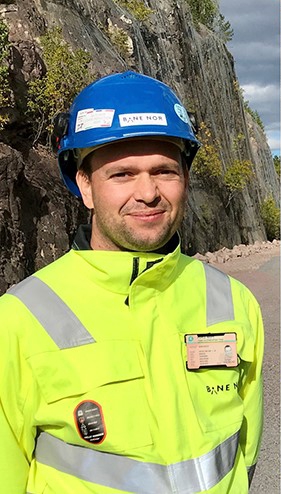 Portrettbilde av Marius Tangerås i gult vernetøy og blå hjelm. 