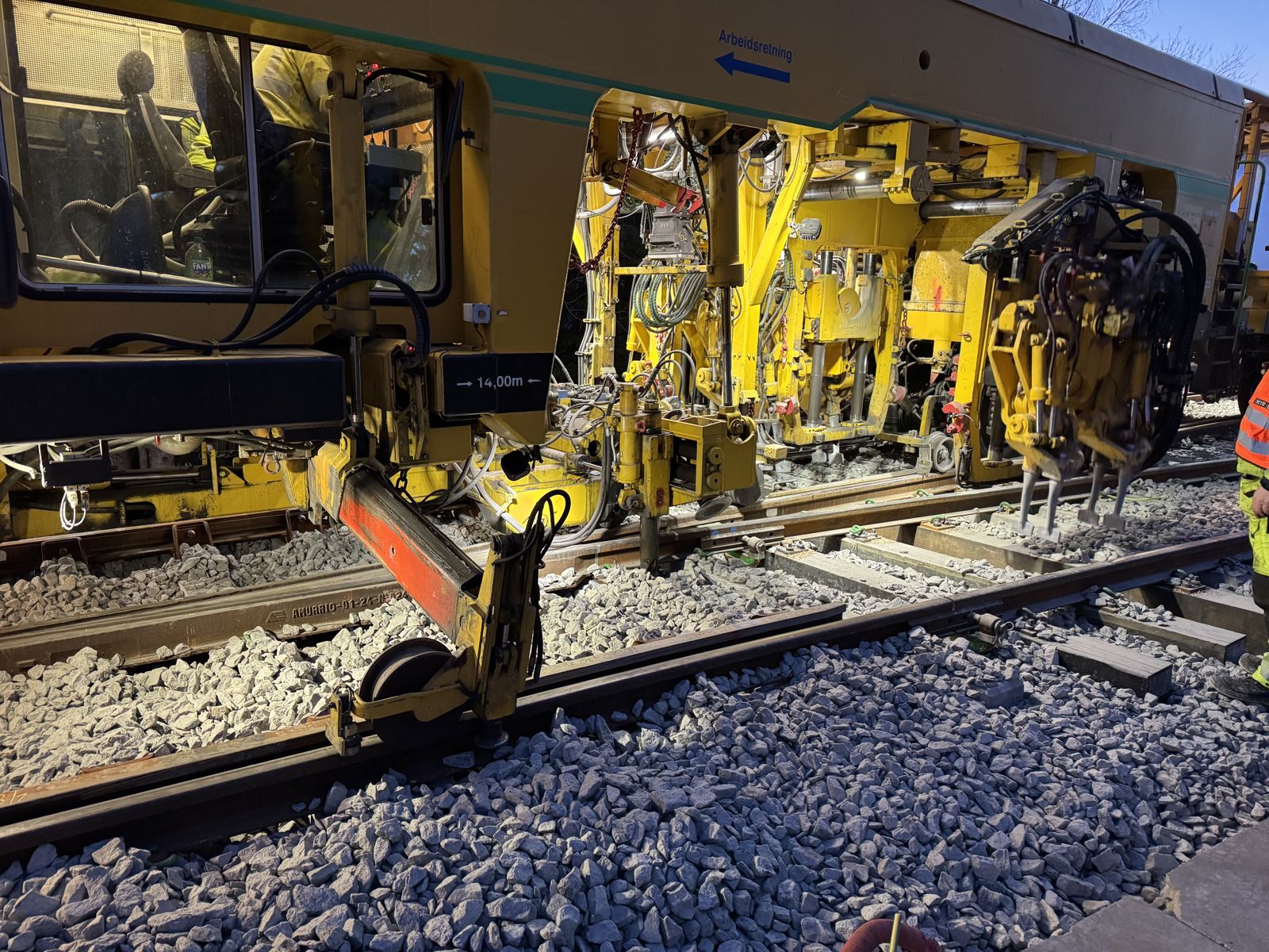 Stor gul arbeidsmaskin jobber på jernbanen.