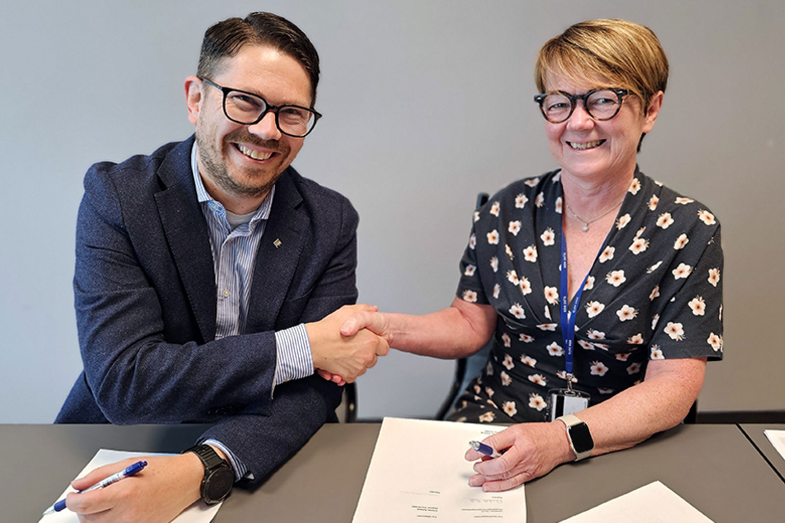 Håndtrykk mellom to smilende mennesker