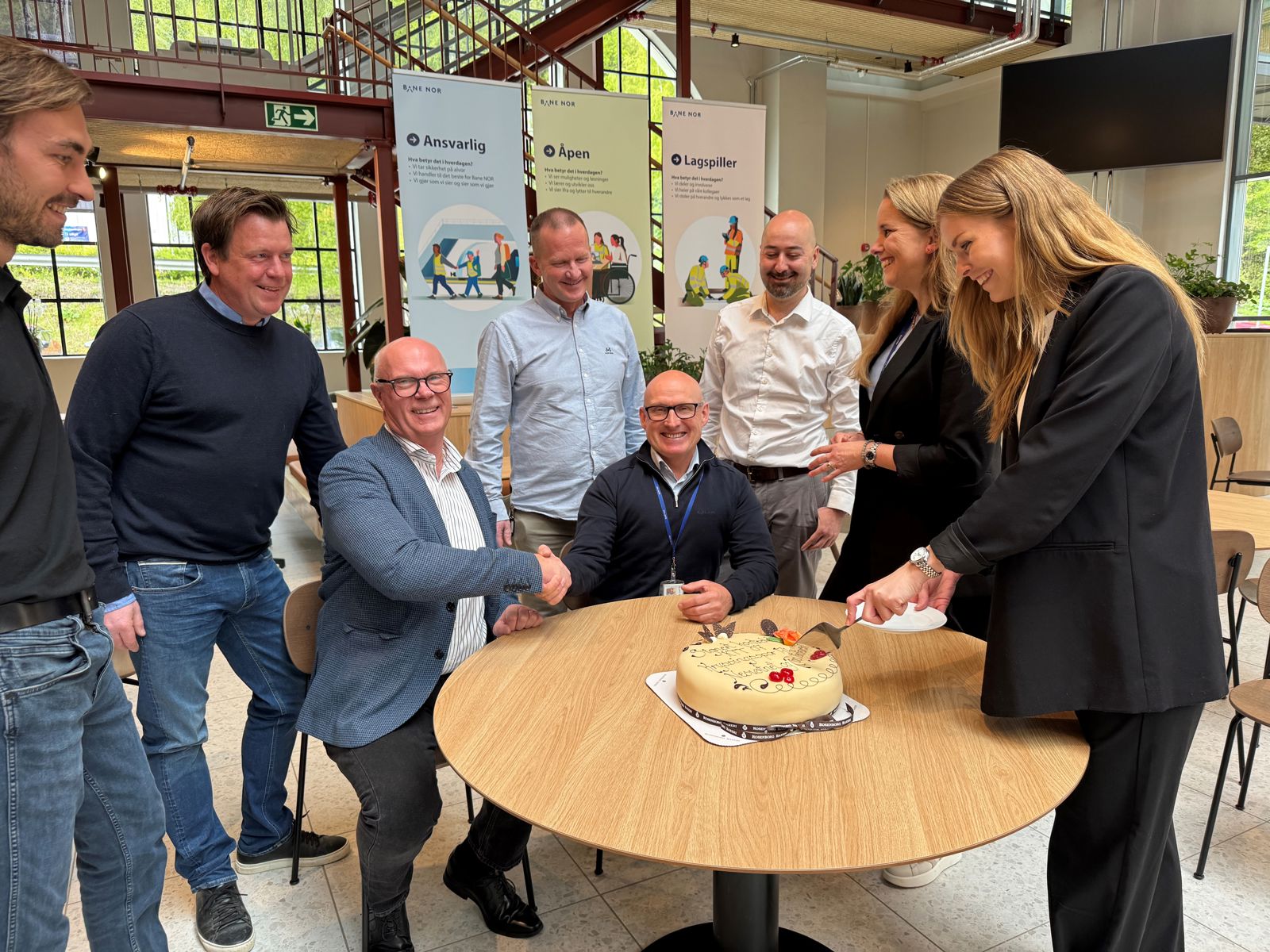Skjærer kake for å feire signering av kontrakt