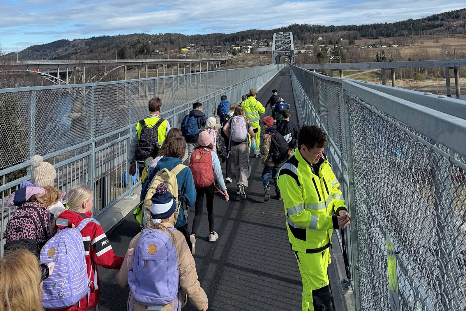 Porten er åpen, elever med ransler går ut på brua. I bakgrunnen de andre bruene på Minnesund.,