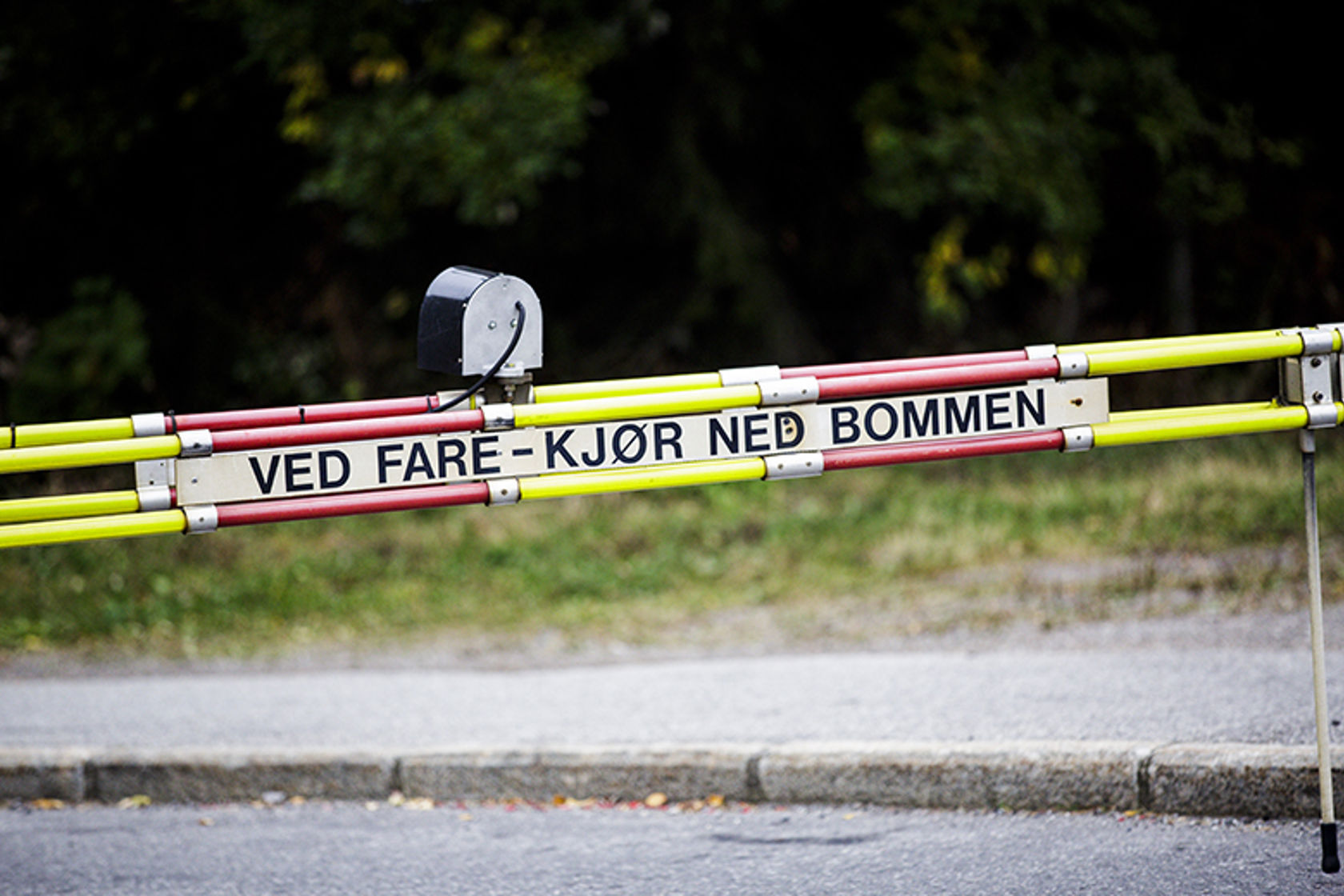 Bom med påskrift om å køyre ned bommen ved fare